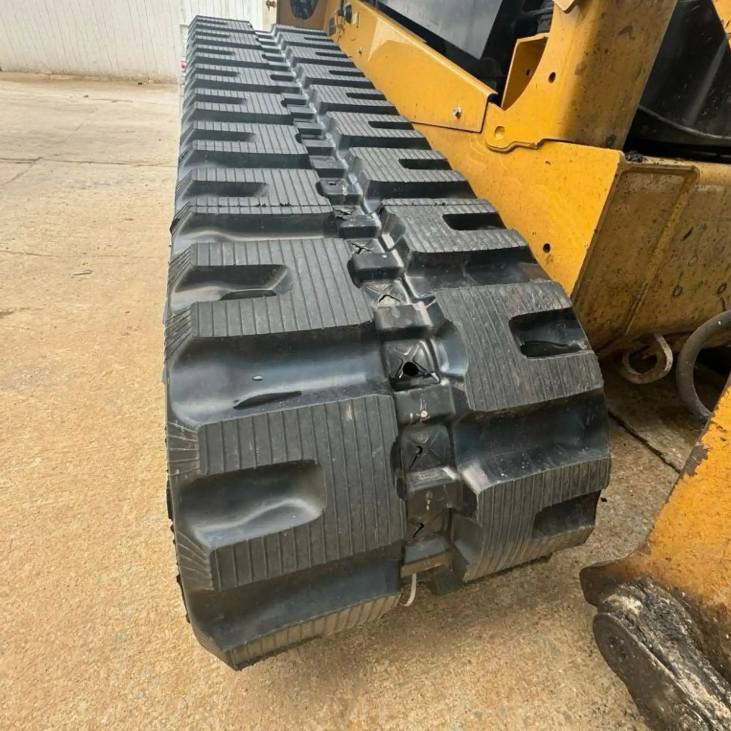 A heavy-duty rubber track with aggressive tread for construction or agricultural equipment.