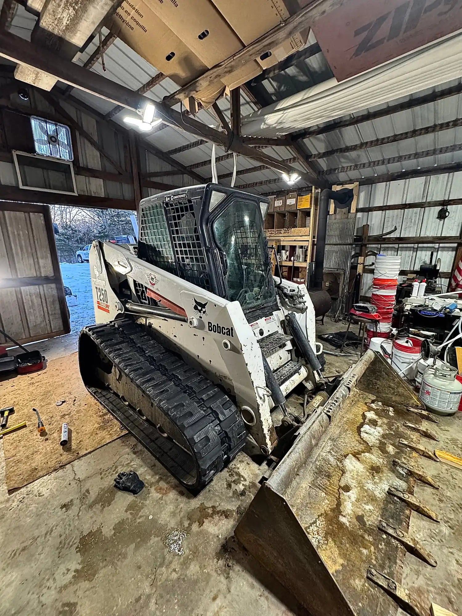 Bobcat T250 track loader in a workshop setting with tools and equipment around