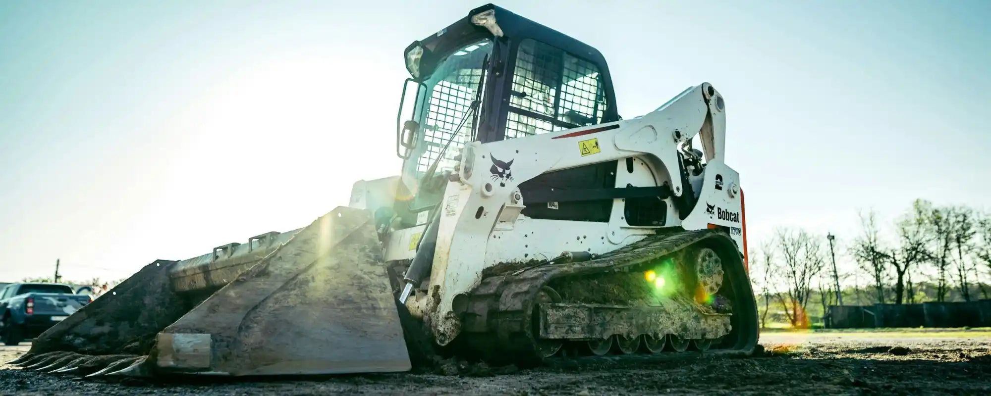 A white Bobcat T770 compact track loader at a construction site, featuring heavy-duty replacement rubber tracks.
