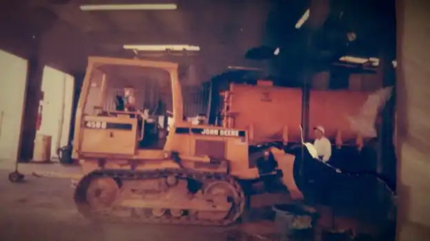 A yellow John Deere crawler dozer with a front blade.